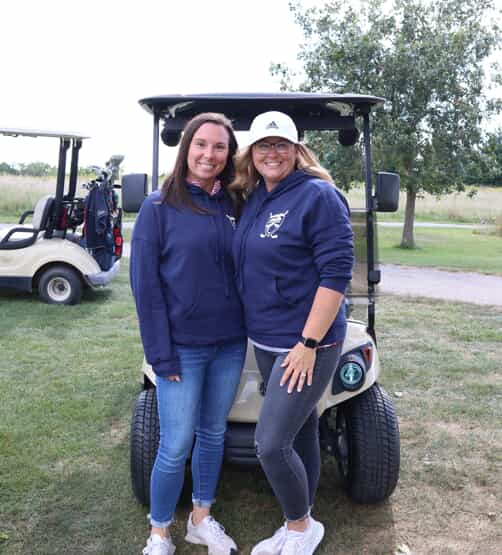 Two women in front of the golf cart