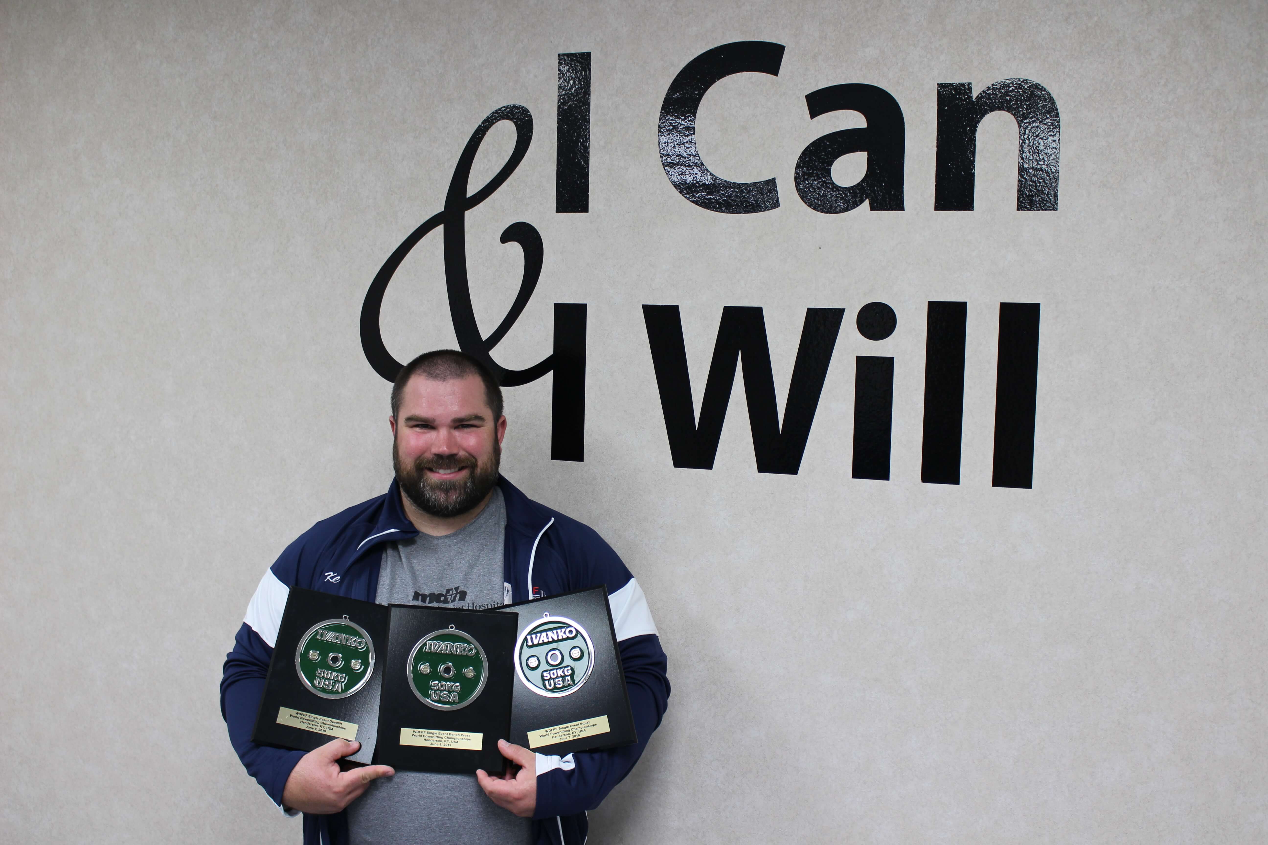 man holding three awards